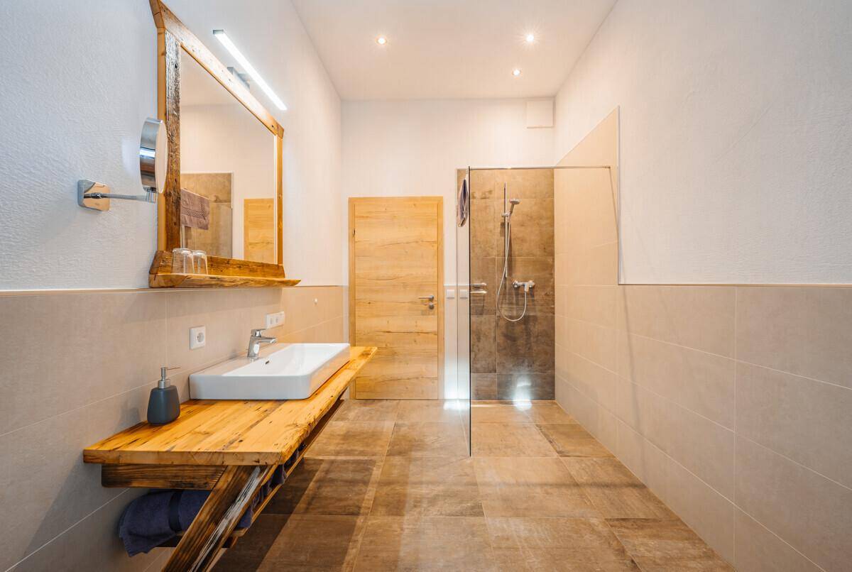 Modernes Badezimmer mit begehbarer Dusche, Holzwaschtisch und hellen Fliesen.