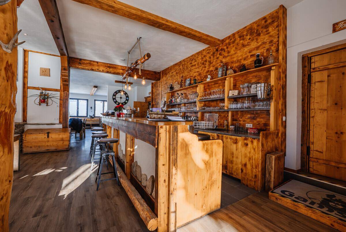 Rustikale Bar mit Holztresen, Regalen und Hockern, ideal für gesellige Abende.
