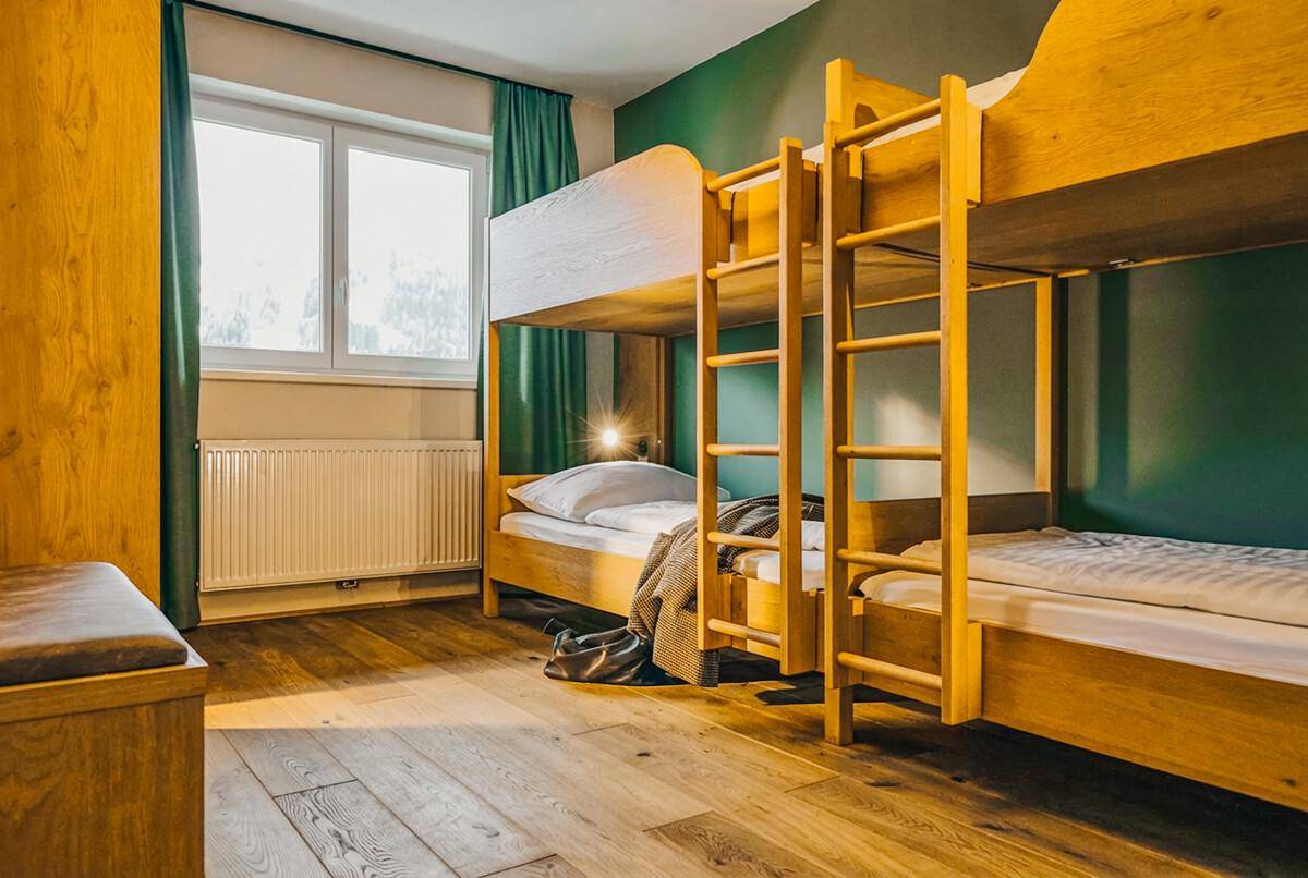 Kinderzimmer mit Etagenbetten aus Holz, Holzboden und grüner Wand, ideal für Familien.
