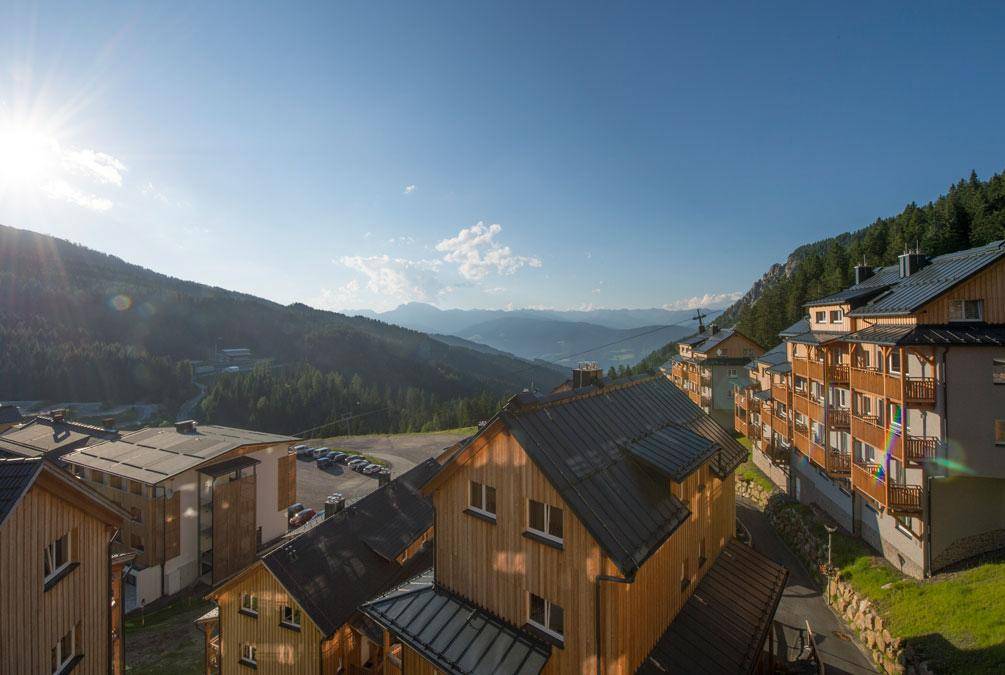Sonniger Ausblick von einem Balkon auf die umliegende Bergwelt und die Ferienanlage.