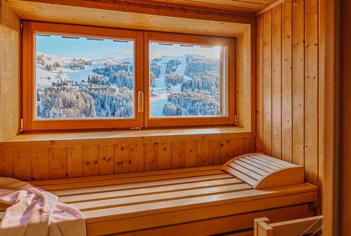 Gemütliche Holzsauna mit Fenster und Blick auf die verschneite Berglandschaft, ideal zur Entspannung.