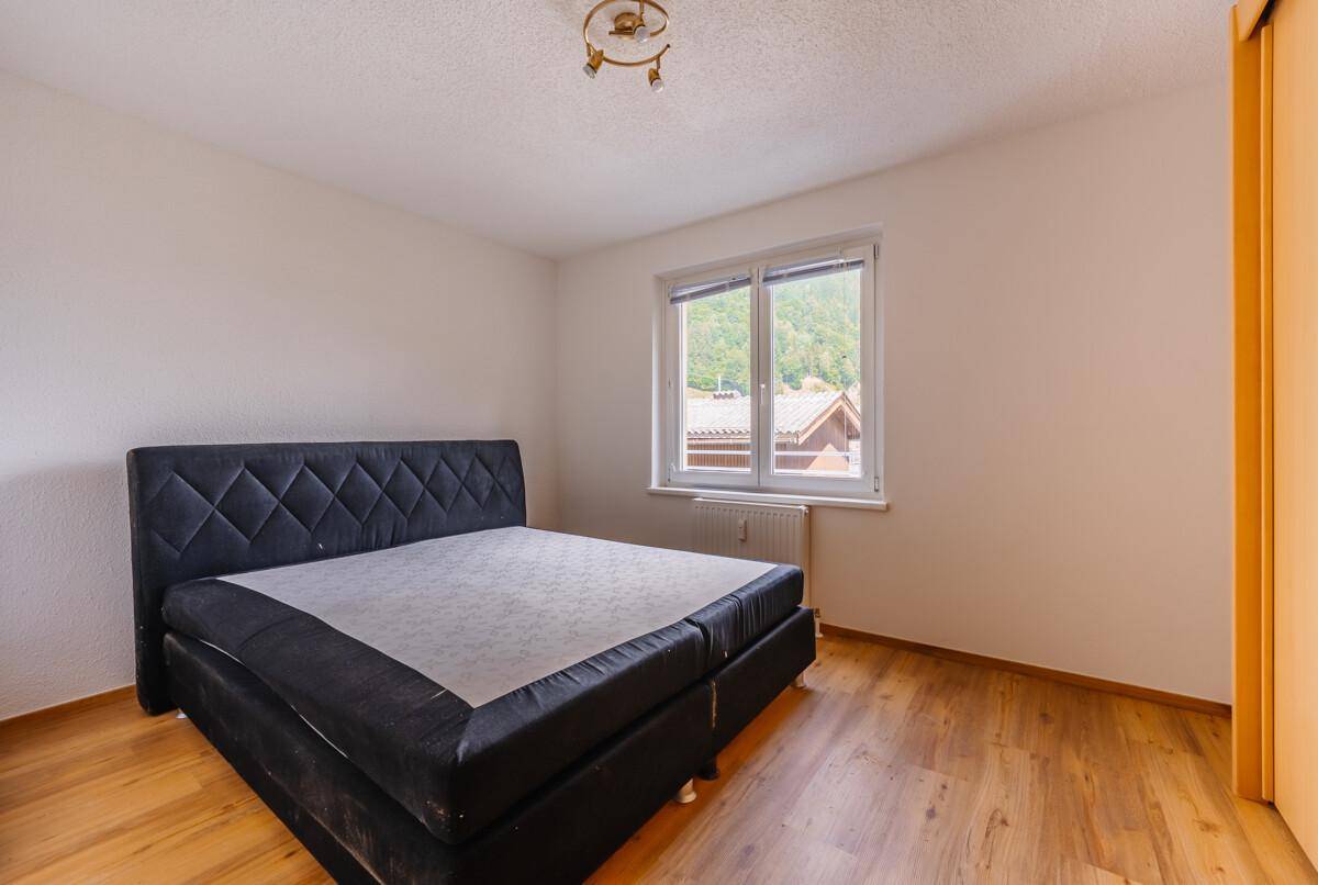Schlafzimmer mit Doppelbett, Holzboden und Fenster mit Blick auf die grüne Umgebung.