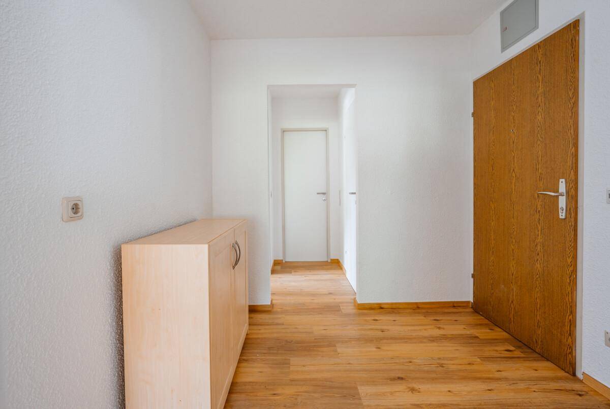 Heller Flur mit Holzboden und einem praktischen Sideboard im Eingangsbereich.