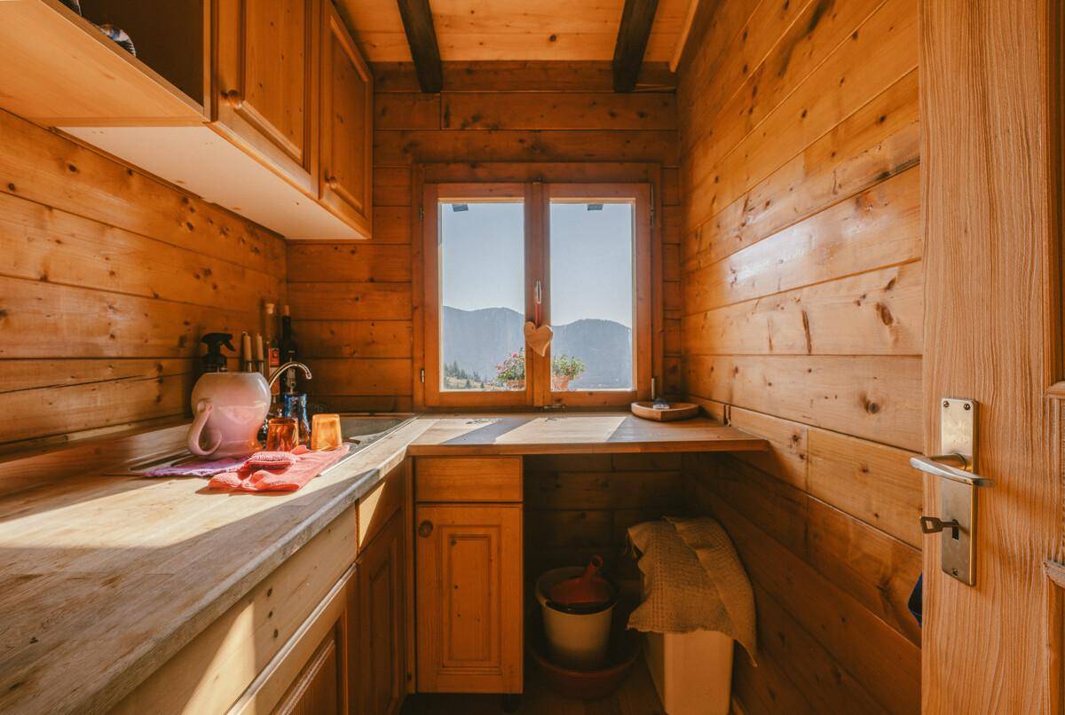 Kleine Holzküche mit Fenster und Blick auf die Berge, ausgestattet mit Spüle und Arbeitsfläche.