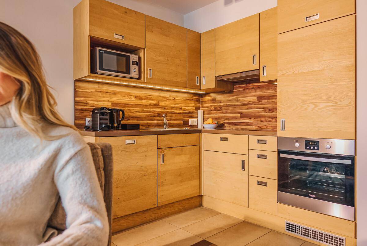 Moderne Holzküche mit integrierten Geräten und heller Arbeitsplatte.
