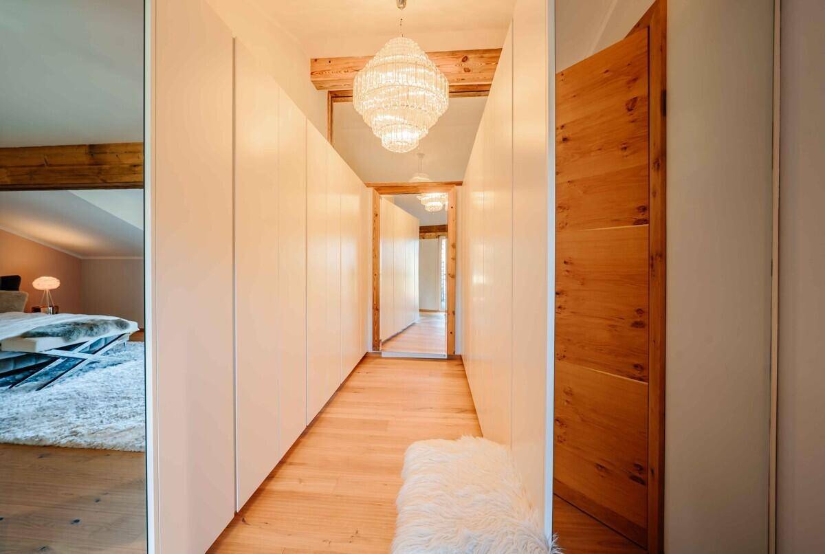 Heller Flur mit Einbauschränken, Holzboden und Kronleuchter.