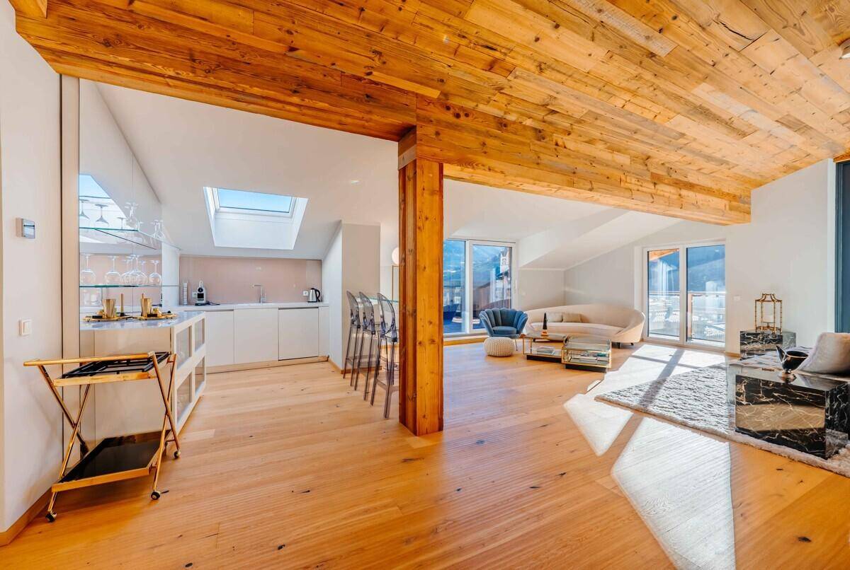 Offener Wohn- und Essbereich mit Holzbalkendecke, Bar und Bergblick.