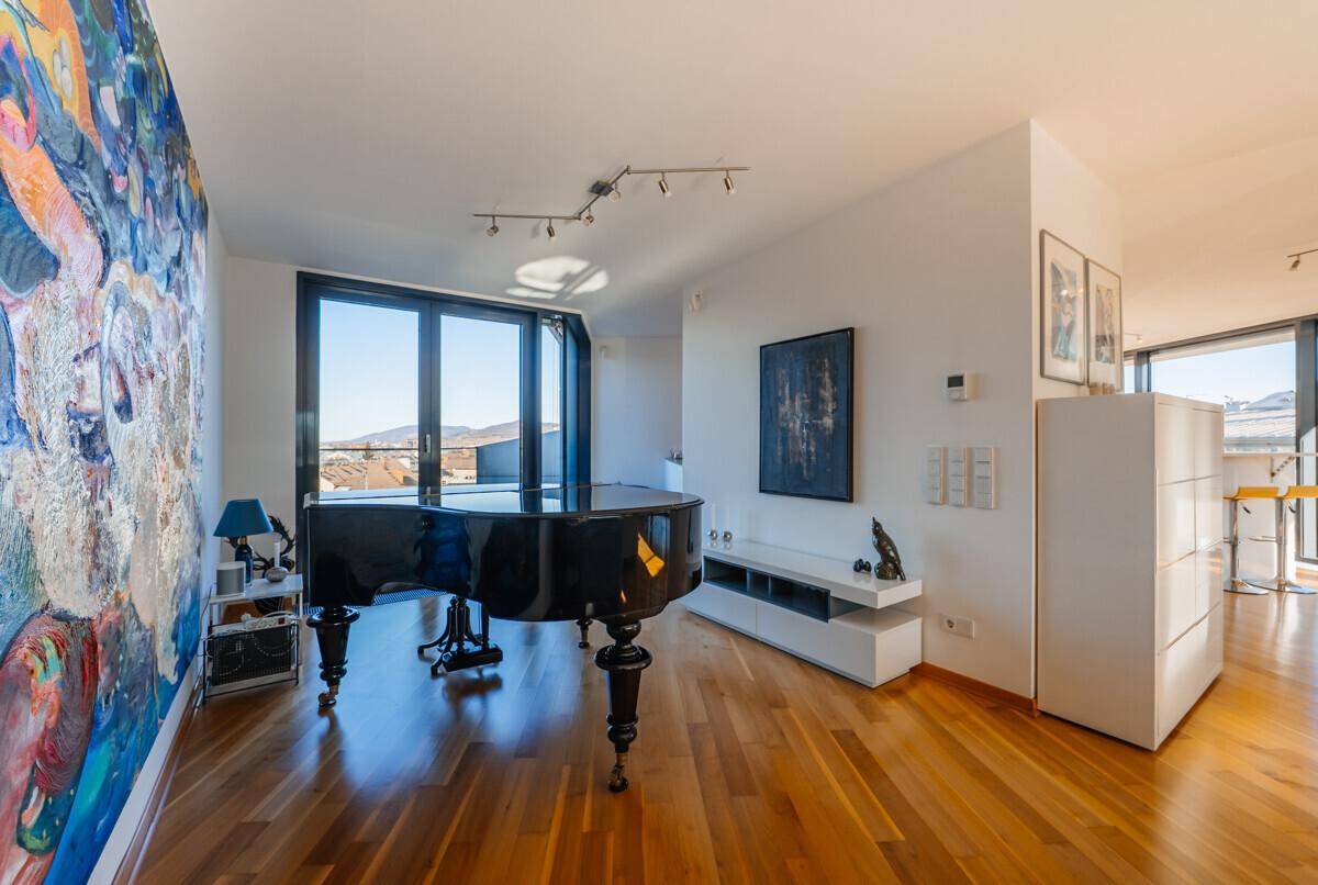 Geräumiges Wohnzimmer mit Flügel, Holzboden und großen Fenstern mit Bergblick.