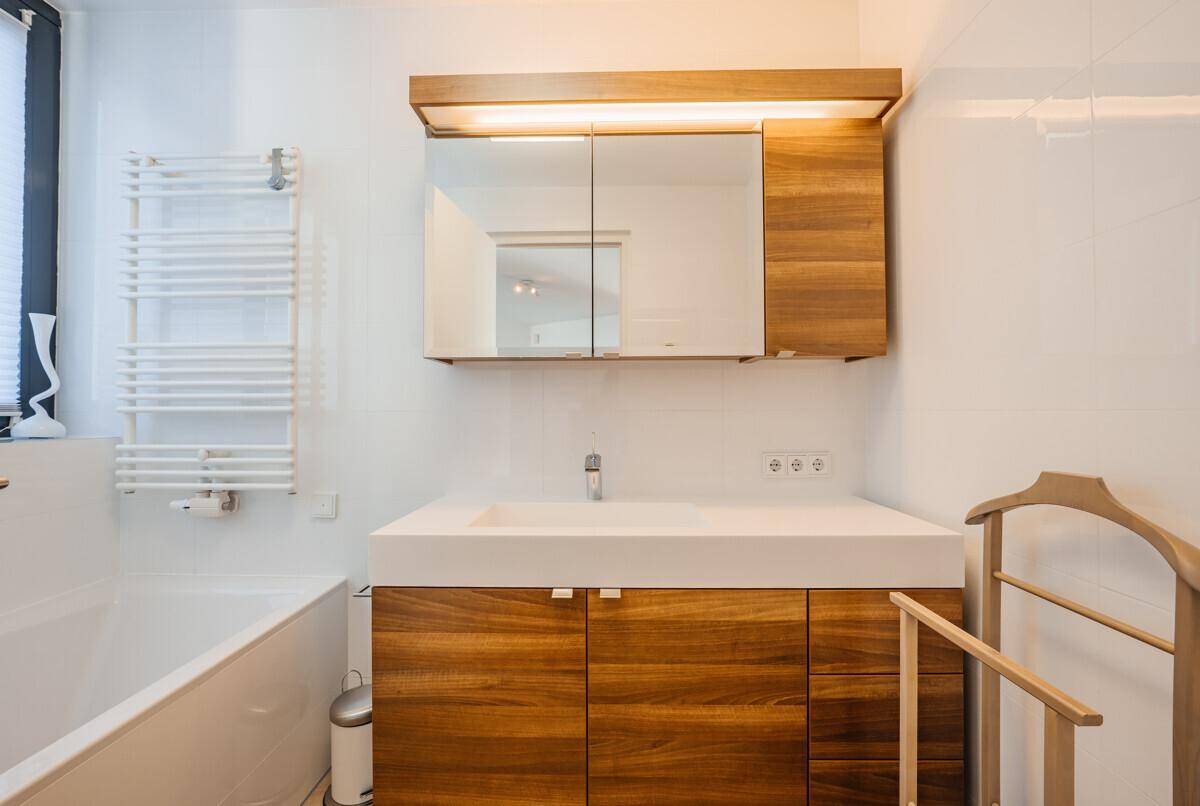 Modernes Badezimmer mit Holzelementen, Badewanne und beheiztem Handtuchhalter.