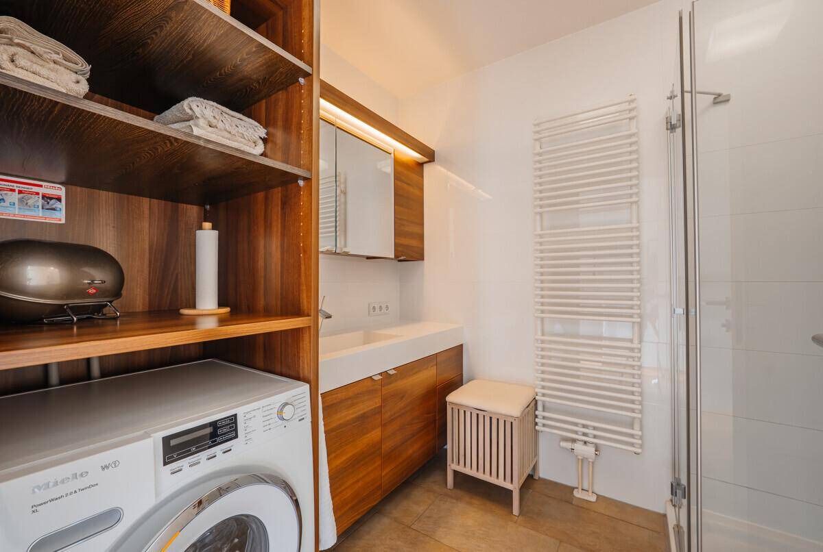 Funktionaler Hauswirtschaftsraum mit Waschmaschine, Trockner und Holzregalen.