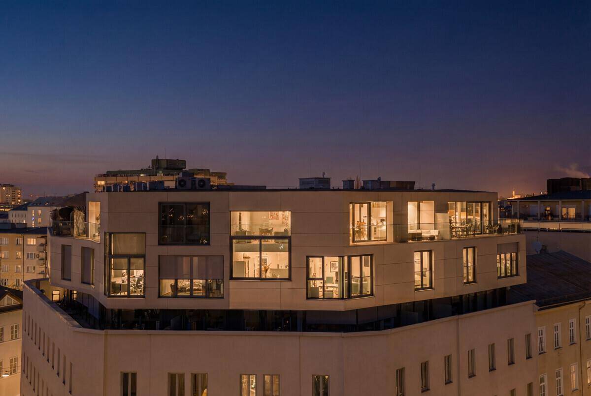 Moderne Dachgeschosswohnung mit großen Fenstern und Terrassen bei Dämmerung.