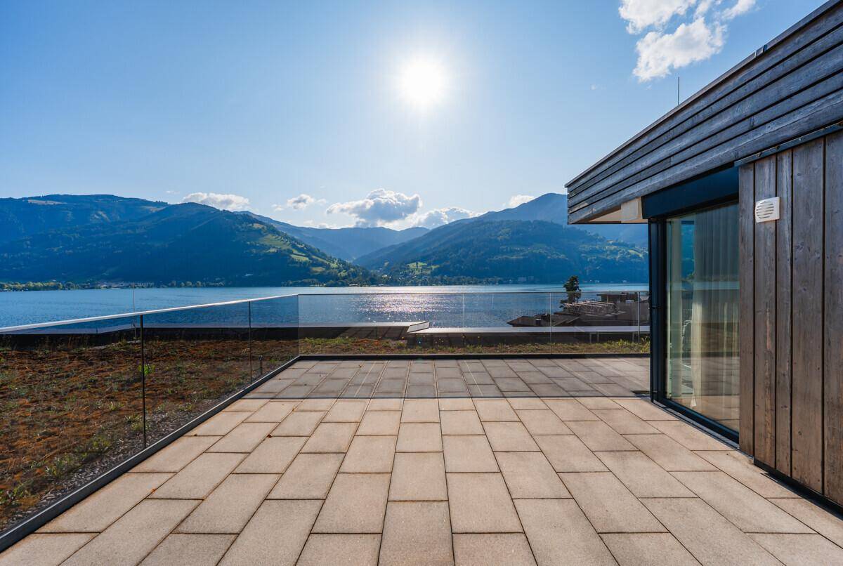Weitläufige Sonnenterrasse mit Fliesenboden und Glasgeländer, bietet einen herrlichen See- und Bergblick.