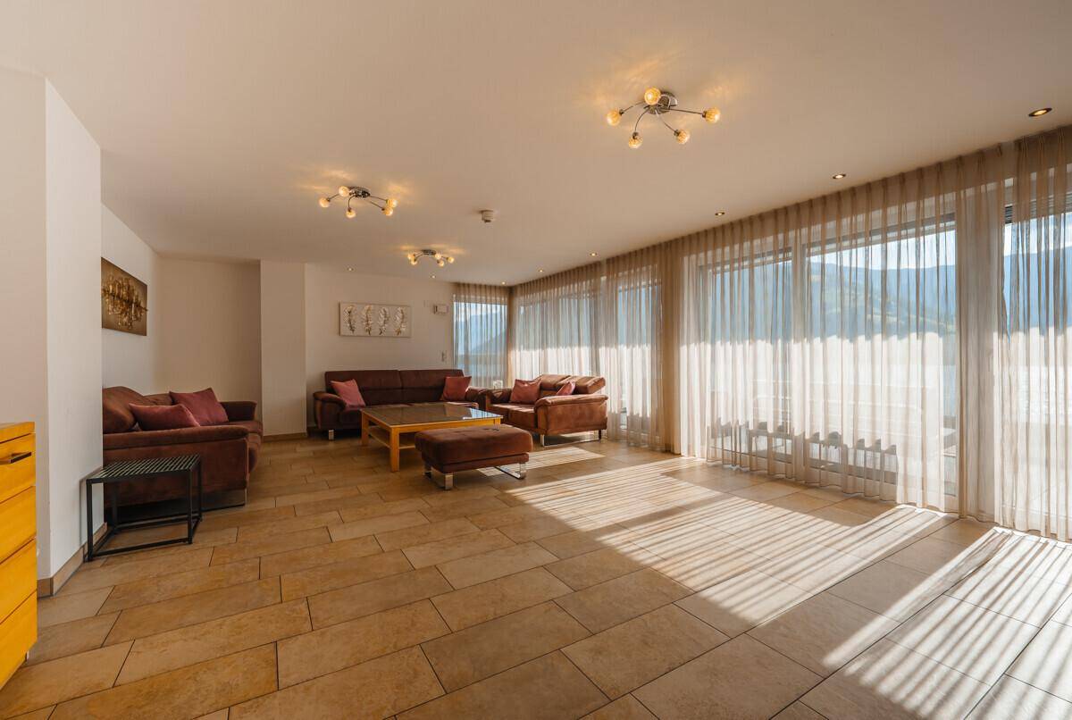 Geräumiges Wohnzimmer mit bequemen Sofas, Fliesenboden und großen Fenstern für viel Tageslicht.