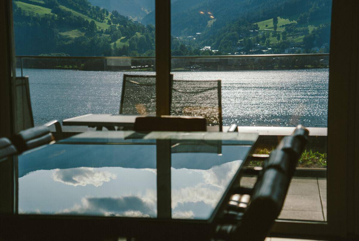 Essbereich mit großem Glastisch und Stühlen, der einen malerischen Blick auf den See bietet.