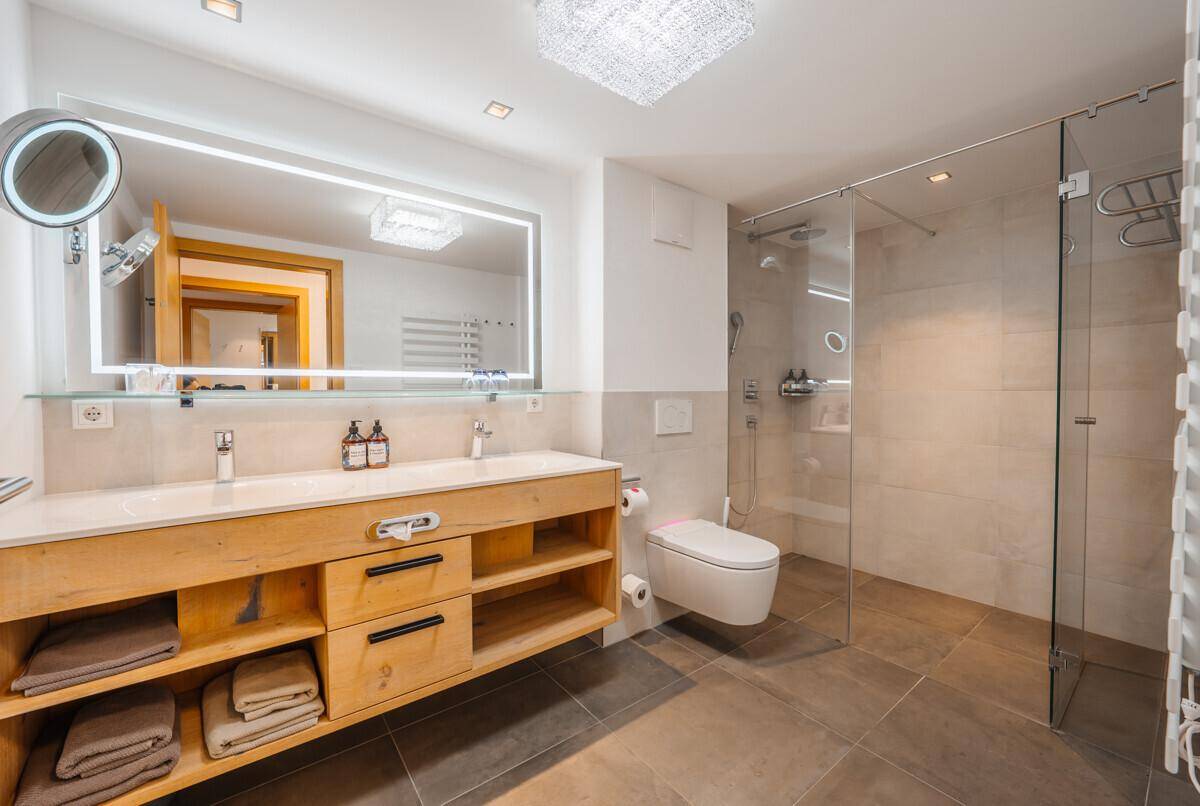 Modernes Badezimmer mit Doppelwaschbecken, begehbarer Dusche und beheiztem Handtuchhalter.