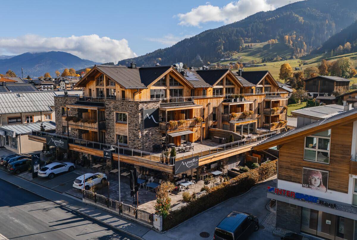 Luxuriöse Wohnanlage im alpinen Stil mit Stein- und Holzfassade in bergiger Umgebung.