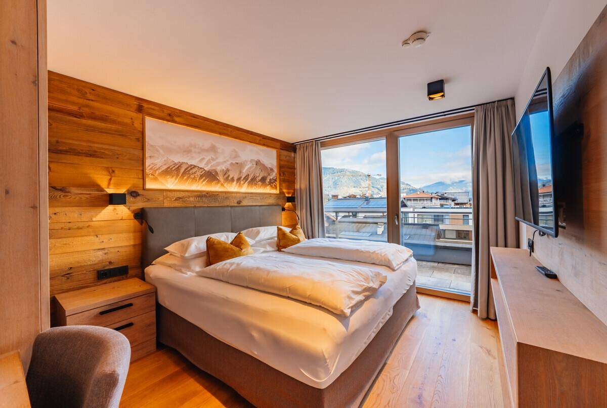Komfortables Schlafzimmer mit Holzwänden, Doppelbett und Zugang zu einem Balkon.
