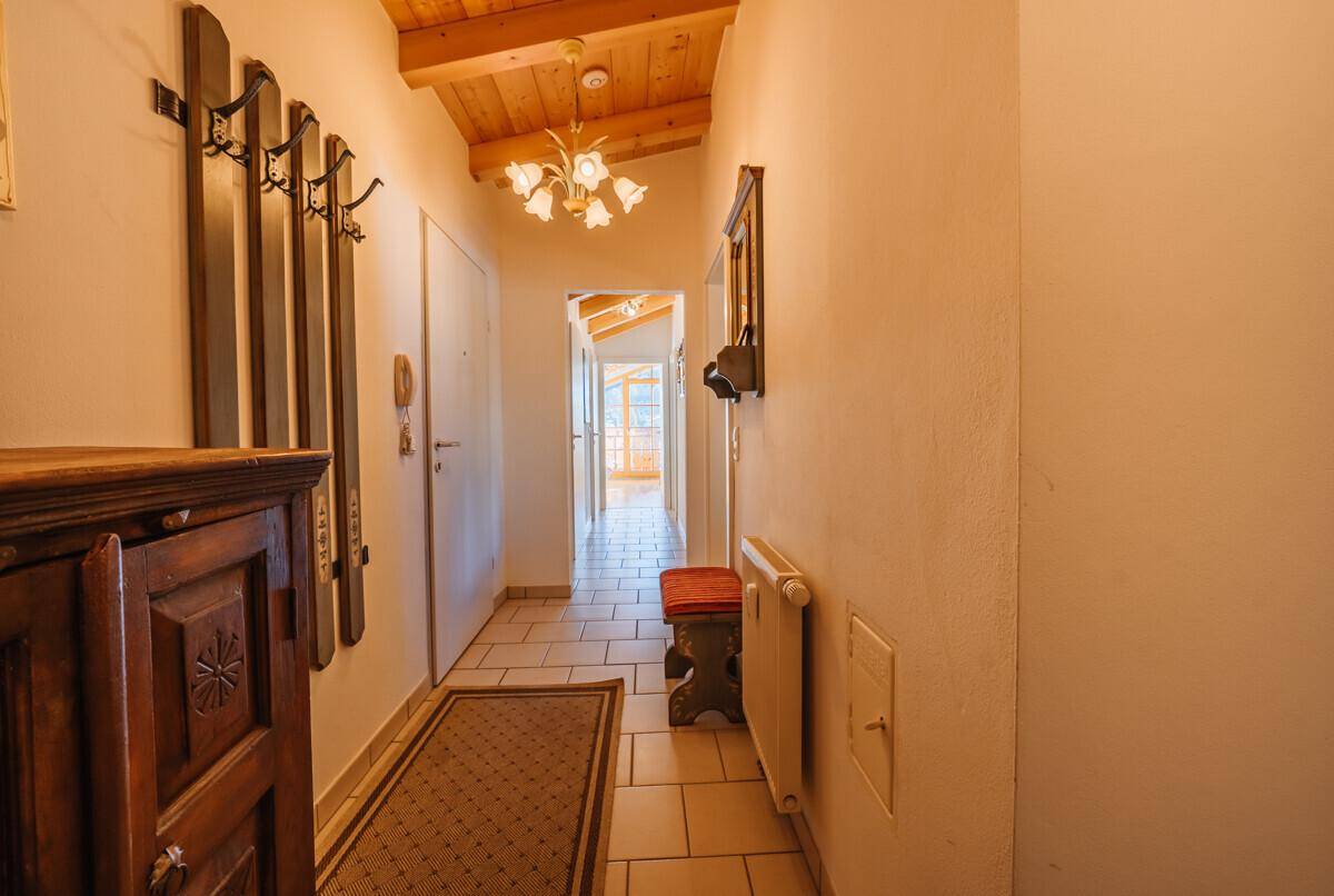 Heller Flur mit Fliesenboden, Garderobe und Holzbalkendecke.