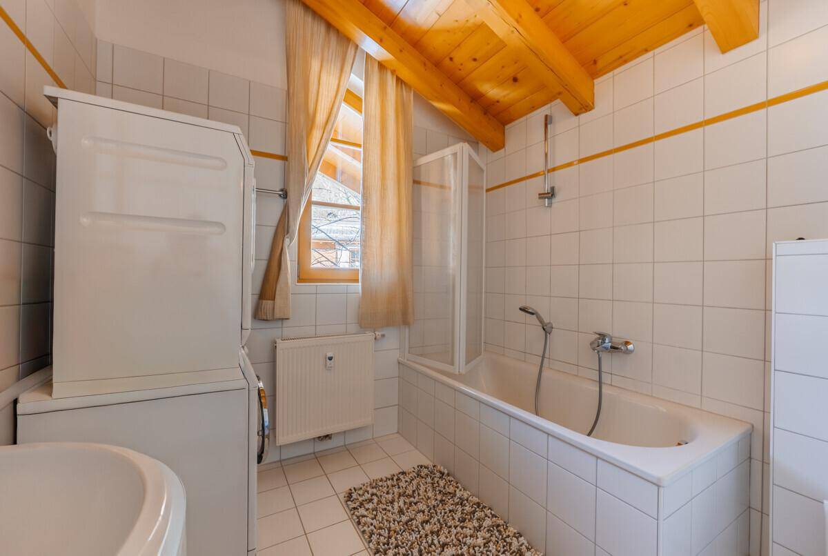 Helles Badezimmer mit Badewanne, Dusche und Fenster.
