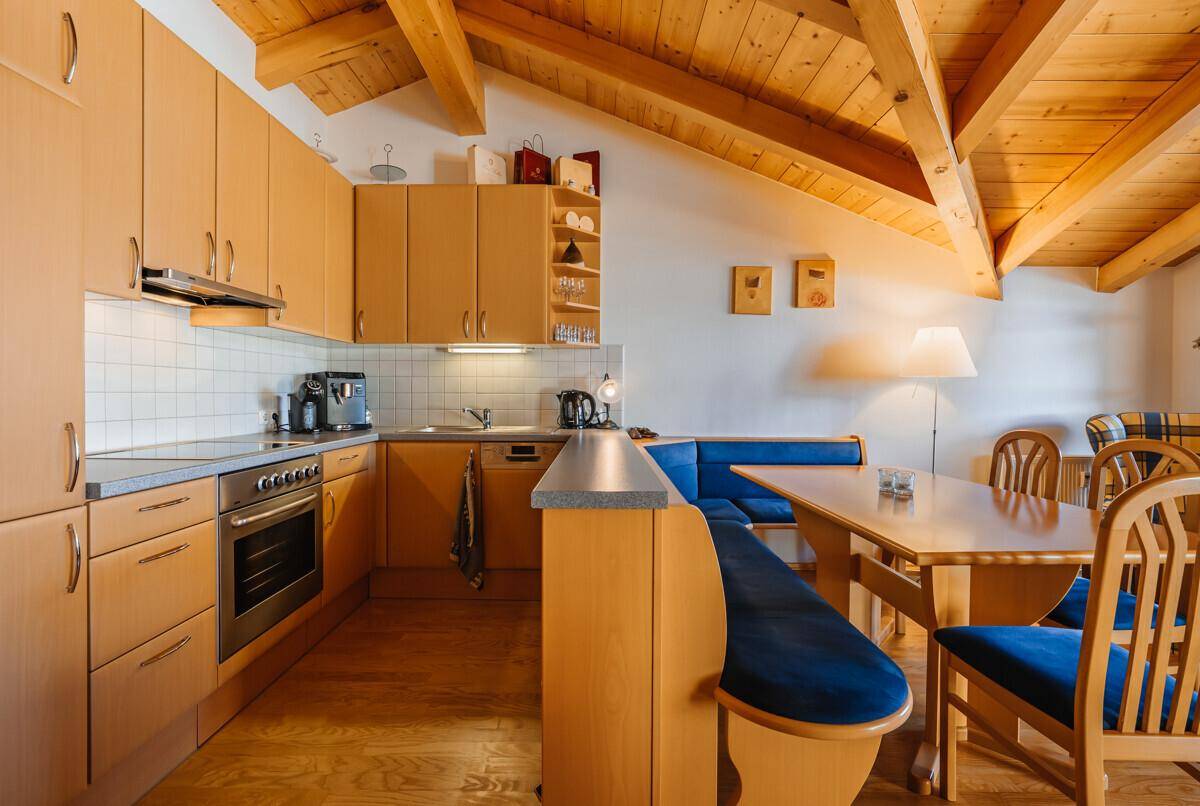 Funktionale Einbauküche mit Holzfronten, modernen Geräten und Essbereich.
