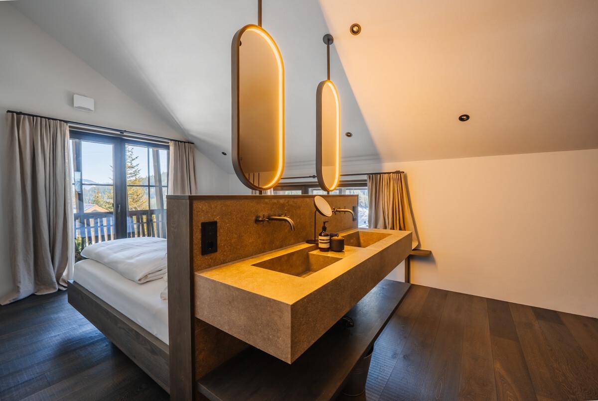 Schlafzimmer mit integriertem Doppelwaschbecken, dunklem Holzboden und Dachschräge.