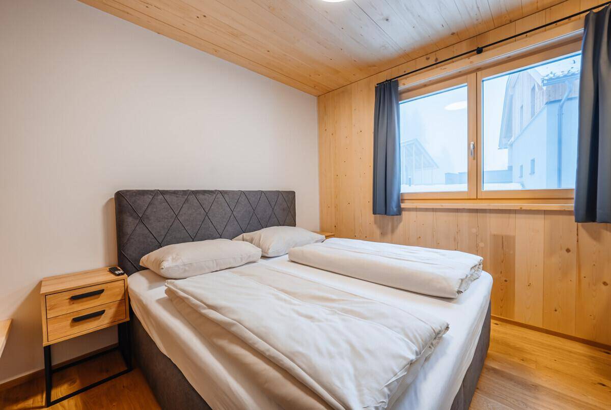 Helles Schlafzimmer mit Doppelbett, Holzwänden und Holzboden in modernem Stil.