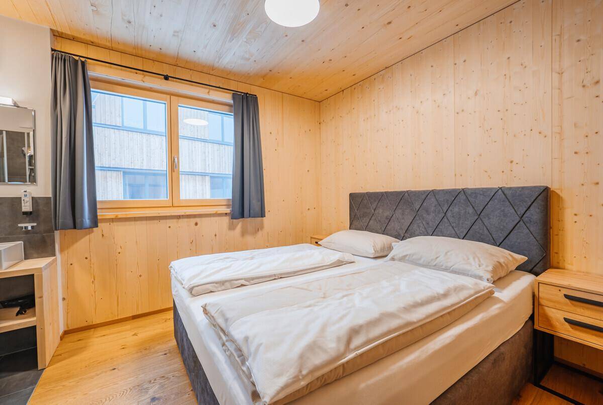 Helles Schlafzimmer mit Holzwänden, bequemen Doppelbett und Fenster für Tageslicht.