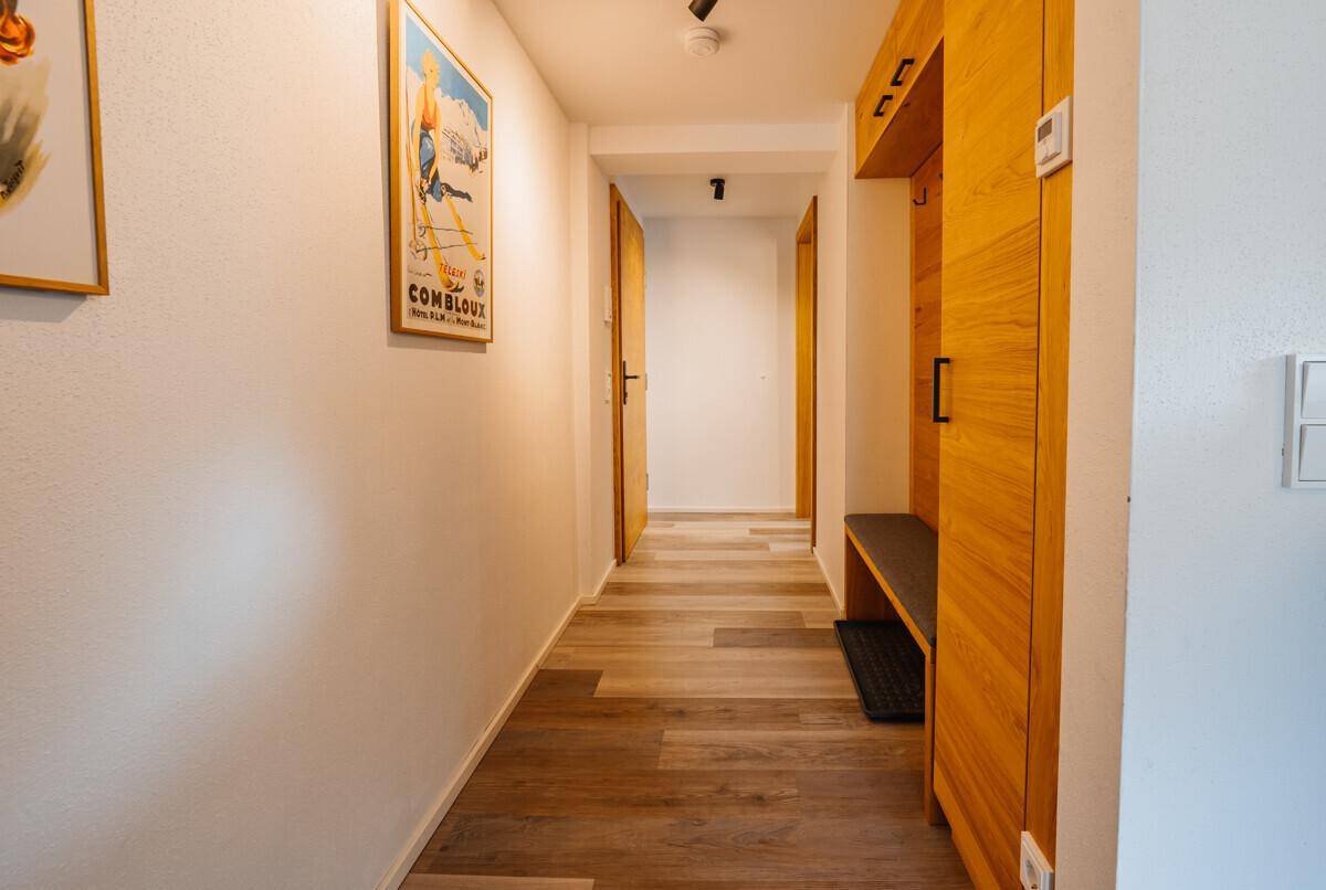 Heller Flur mit Garderobe aus Holz und modernem Bodenbelag, einladend und funktional gestaltet.