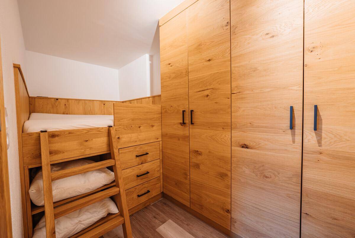 Kinderzimmer mit Etagenbett und geräumigen Holzschränken für Stauraum, funktional und hell.