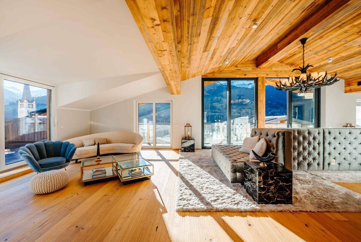 Gemütliches Wohnzimmer mit Holzbalkendecke, bequemen Sofas und Panoramablick auf die Berge.