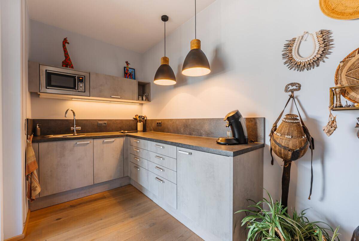 Moderne Küchenzeile mit Spüle, Mikrowelle und grauen Schränken, passend zum zeitgenössischen Design.