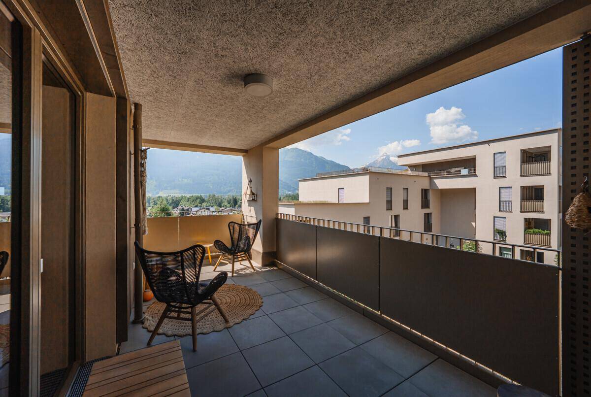 Möblierter Balkon mit Fliesenboden und bequemen Stühlen, bietet einen schönen Blick auf die Berge.
