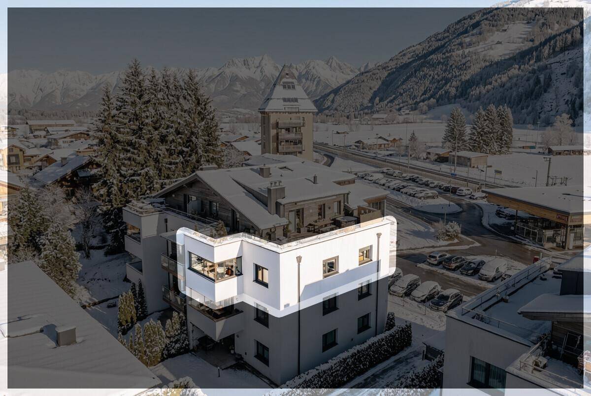 Luftaufnahme eines modernen Wohngebäudes mit Bergblick in einer verschneiten Winterlandschaft.
