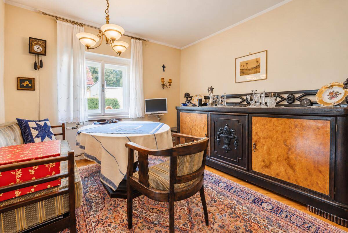 Klassischer Essbereich mit Holzboden, antikem Sideboard und einem runden Esstisch.