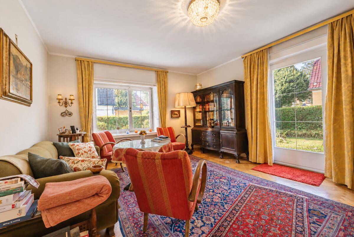 Gemütliches Wohnzimmer mit traditionellen Möbeln, Teppich und Zugang zum Garten.