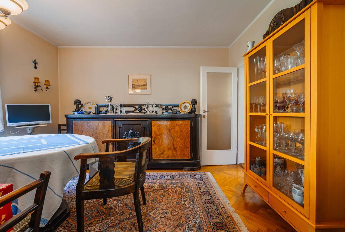 Esszimmer mit traditionellen Möbeln, Holzboden und einem Vitrinenschrank voller Gläser.