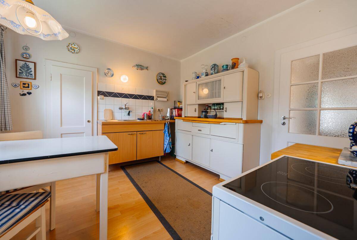Funktionale Küche mit Holzboden, traditionellen Schränken und einem Induktionskochfeld.