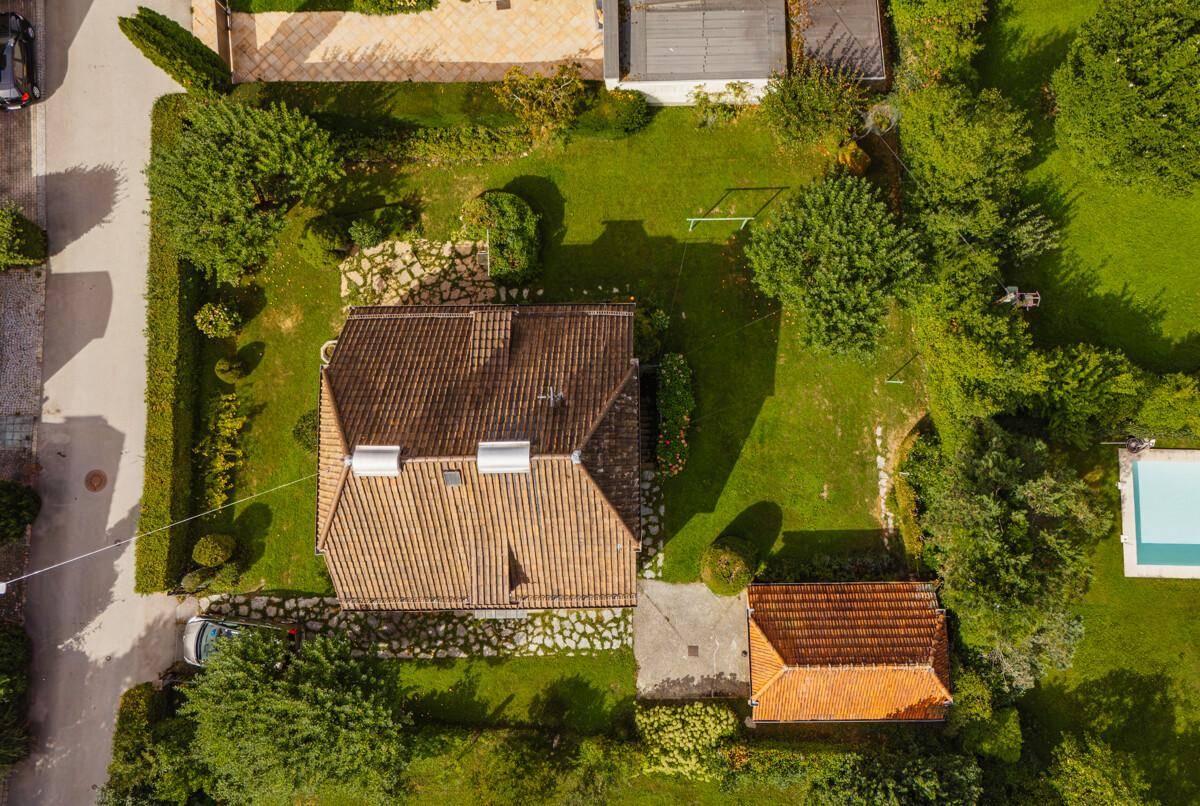 Luftaufnahme des Hauses mit Ziegeldach, großem Garten und angrenzendem Poolbereich.