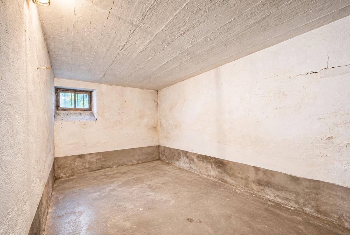 Unfertiger Kellerraum mit Betonboden, kleinen Fenstern und rauen Wänden.
