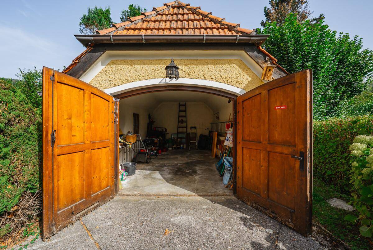 Offene Garage mit Holztoren, die einen Blick auf den Innenraum und Werkzeuge freigibt.