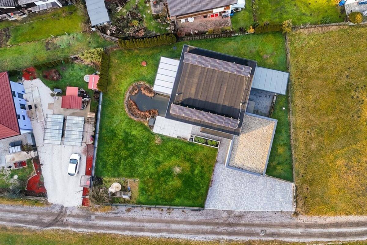 Vogelperspektive des Anwesens mit Photovoltaikanlage, Teich, Garten und Zufahrt.