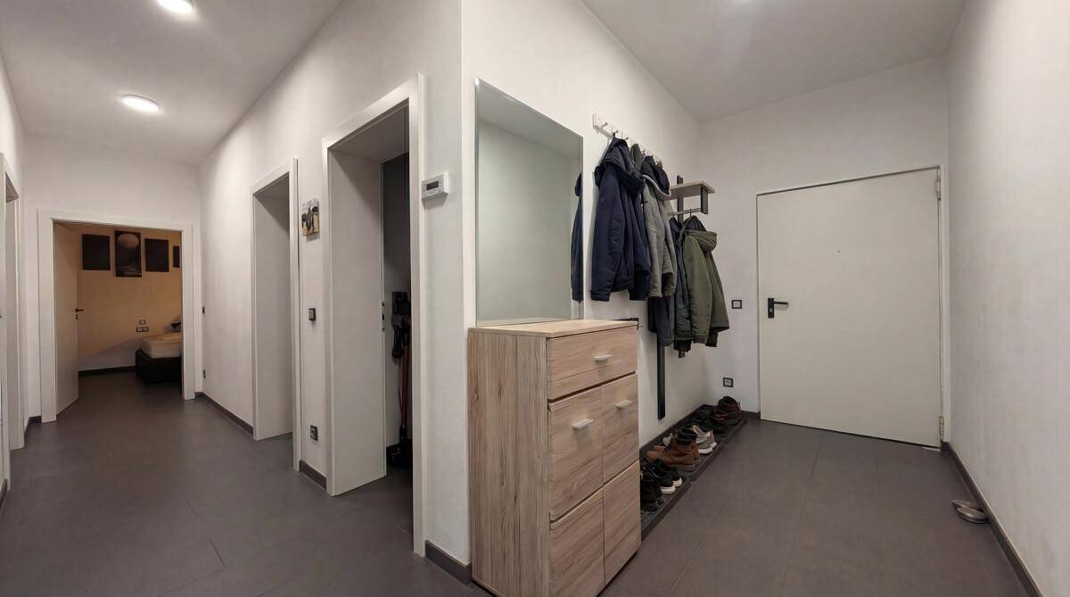 Heller Flur mit Garderobe, Schuhregal und Zugang zu weiteren Zimmern der Wohnung.