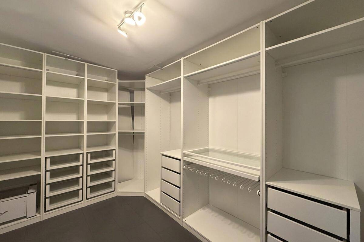 Geräumiger begehbarer Kleiderschrank mit vielen Regalen und Schubladen für optimale Organisation.