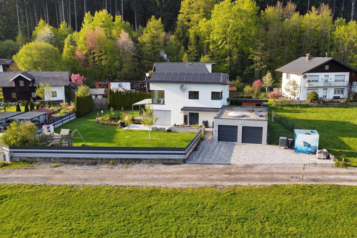 Luftaufnahme des modernen Hauses mit Doppelgarage, Garten und Photovoltaikanlage auf dem Dach.