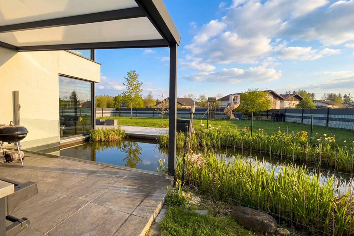 Große Terrasse mit Blick auf den Teich und den weitläufigen Gartenbereich des Anwesens.