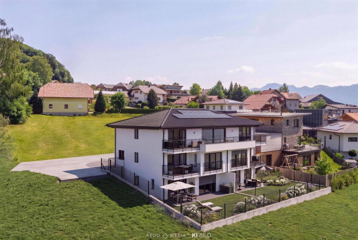 Moderne Wohnanlage am Tag mit Balkonen, Garten und weitem Blick auf die grüne Landschaft.