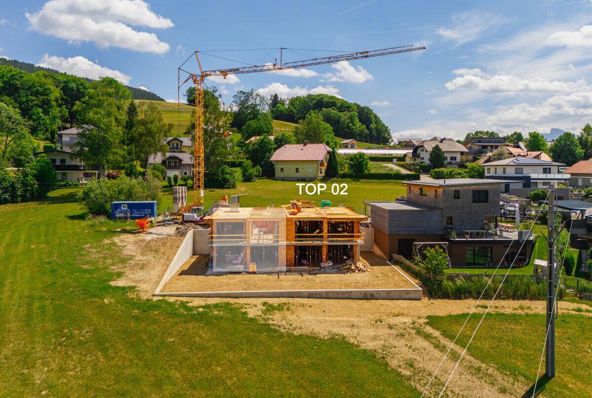 Baustelle eines neuen Hauses mit Kran und teilweiser Holzkonstruktion in ländlicher Umgebung.