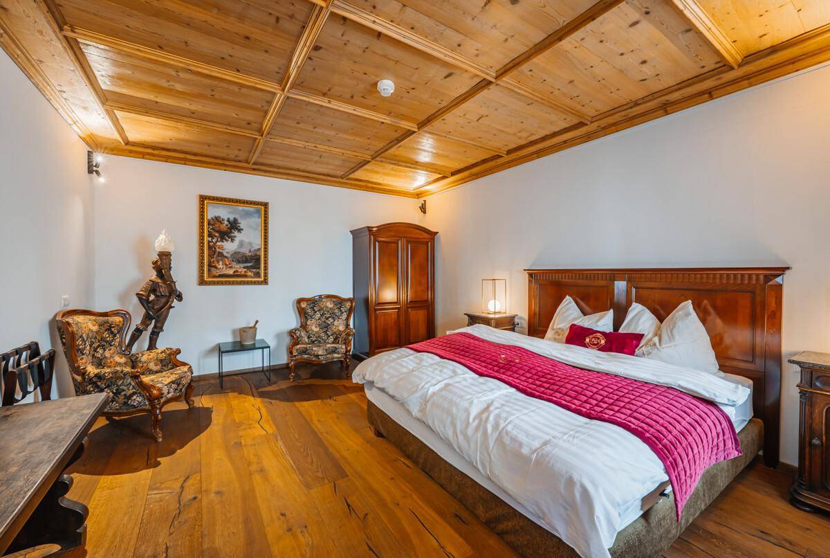 Geräumiges Schlafzimmer mit Holzbalkendecke, breiten Dielen und traditionellen Möbeln.