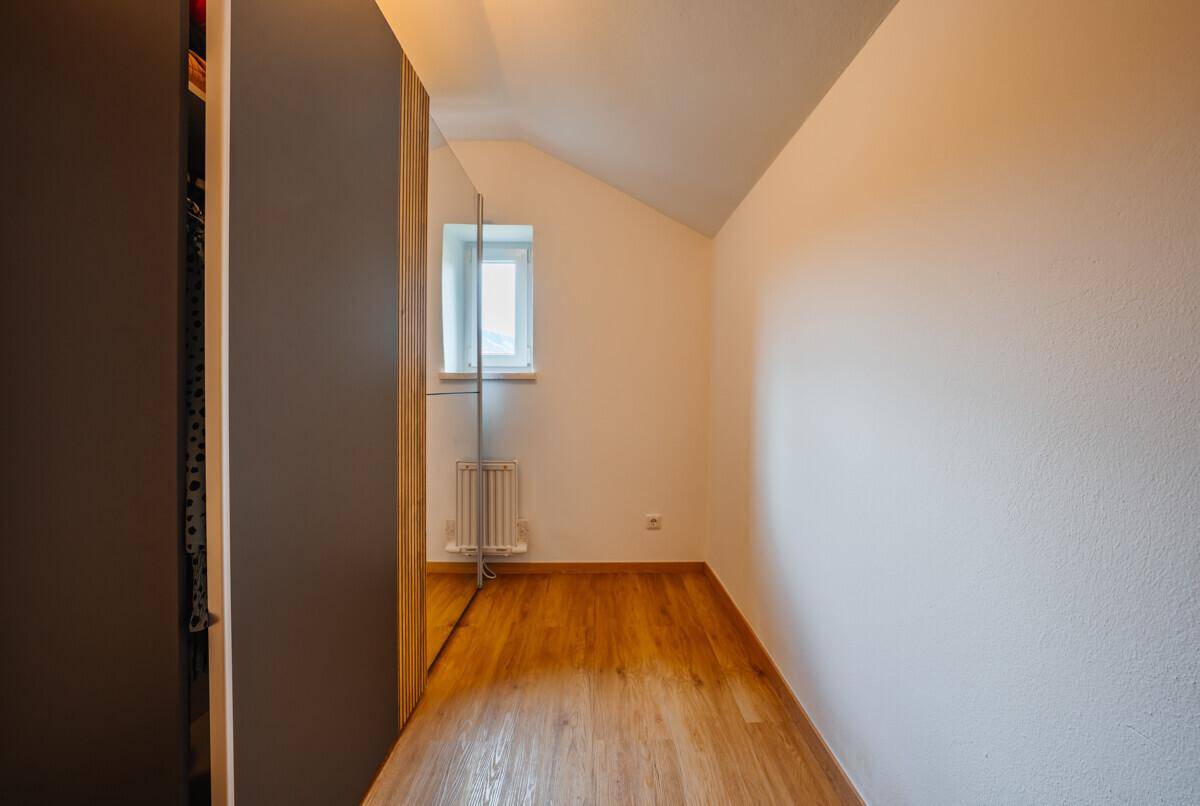Kleiner Raum mit Dachschräge, Holzboden und einem Fenster, ideal als Ankleidezimmer oder Abstellraum.