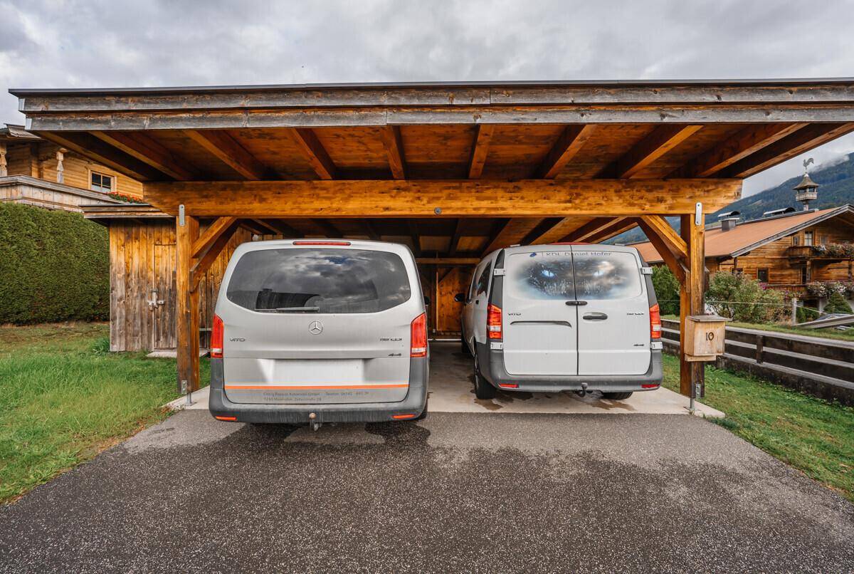 Geräumiger Holzcarport bietet geschützten Stellplatz für zwei Fahrzeuge auf dem Grundstück.